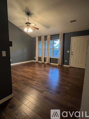 A room with wooden flooring and a ceiling fan.