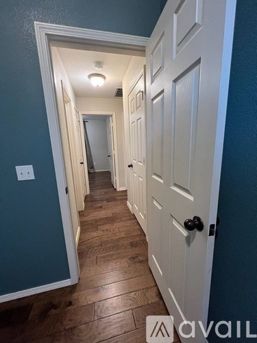 A hallway with white doors and a light switch on the wall.