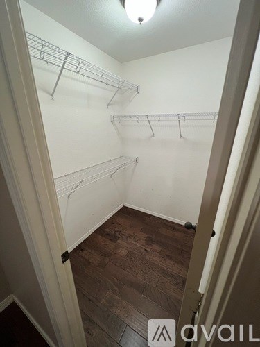 A walk in closet with a white door and shelves.