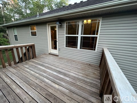 A deck with a railing and a door leading to a house.
