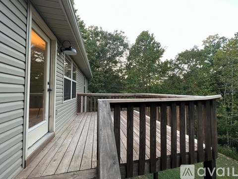 A deck with a railing and a sliding glass door leading to a screened porch.