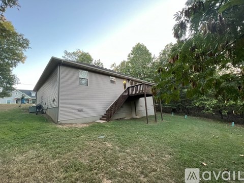 A house with a backyard and a tree in front of it.