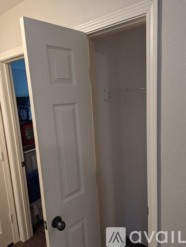 A white door is open to a room with a coat hanger on the wall.