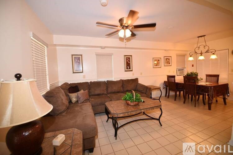 A living room with a brown couch and a ceiling fan.