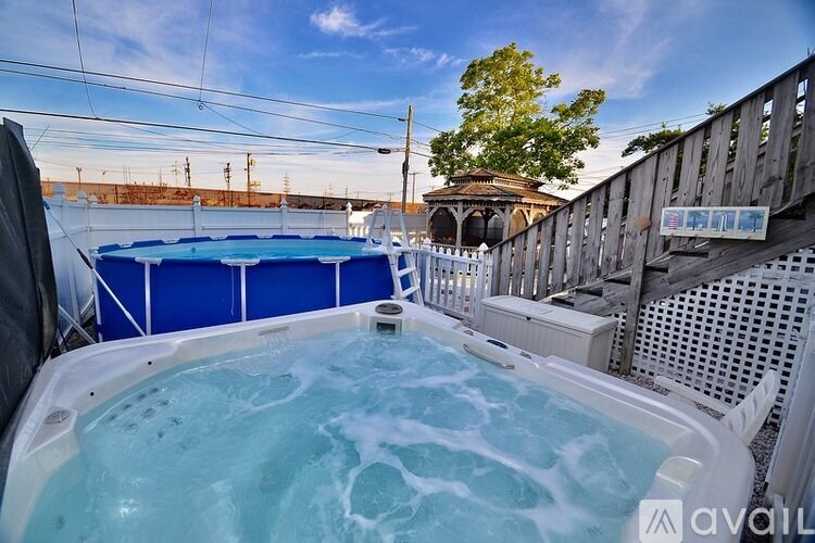 A hot tub on a patio with a wooden fence and a tree in the background.