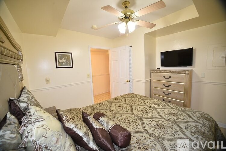 A bedroom with a bed, dresser, and television.