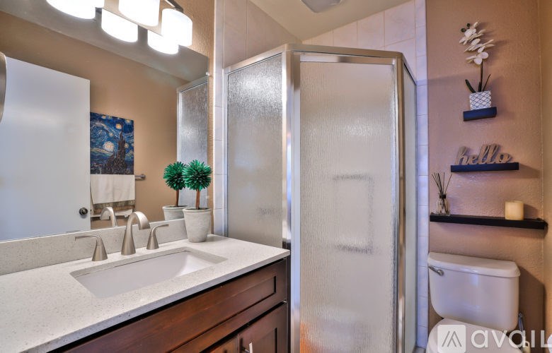 A bathroom with a white sink and a frosted glass shower door.