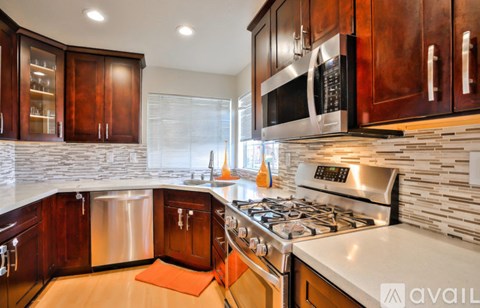 A kitchen with dark wood cabinets and a stainless steel dishwasher.