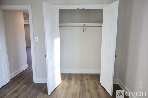 A white closet with a wooden floor and a white door.