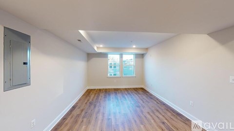A spacious room with wooden floors and a window with blinds.
