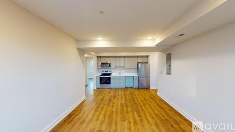 A spacious room with wooden floors and white walls, equipped with a kitchenette.