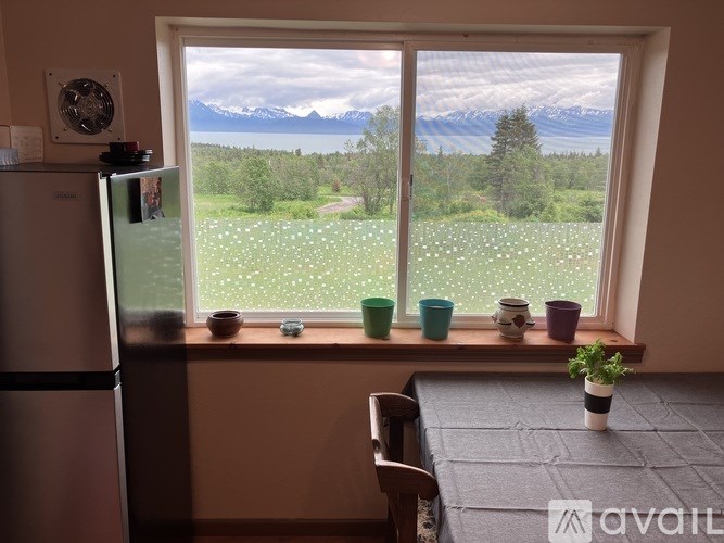 A kitchen with a view of a green field and mountains.