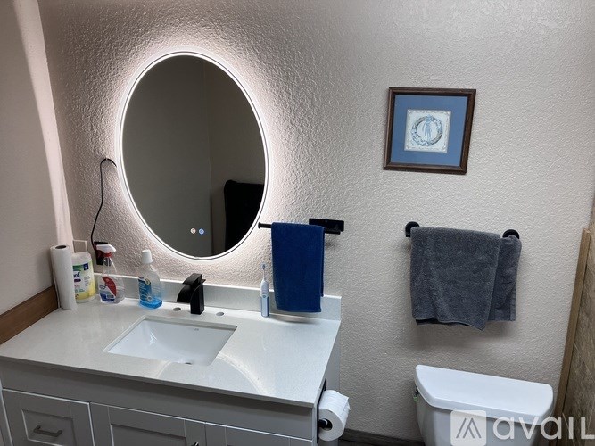 A bathroom with a white sink and a round mirror.