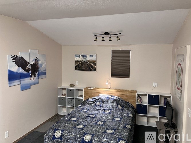 A bedroom with a bed, nightstands, and pictures on the wall.