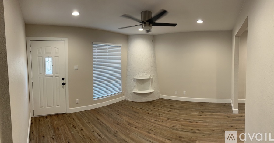 A room with a white door, a ceiling fan, and a shelf.