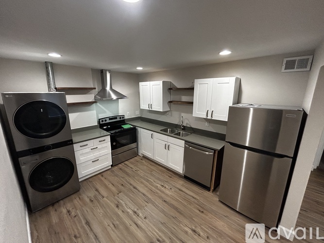 A modern kitchen with stainless steel appliances and wooden flooring.