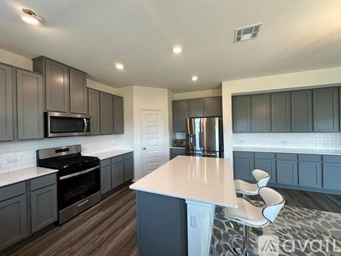 A kitchen with a white island and dark grey cabinets.