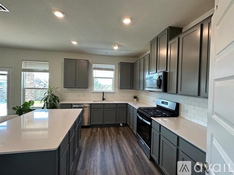 A kitchen with dark wood floors and white countertops.