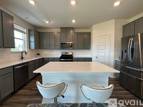 A modern kitchen with a center island and white chairs.