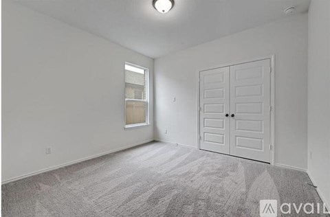 A room with a carpeted floor, a white door, and a window with blinds.