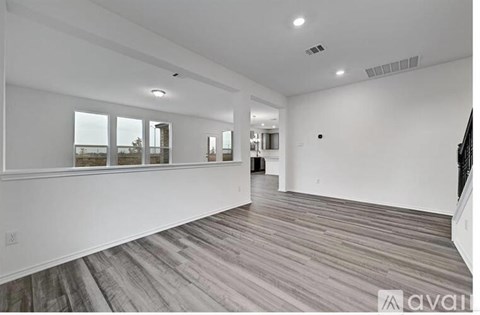 A spacious room with wooden flooring and large windows.