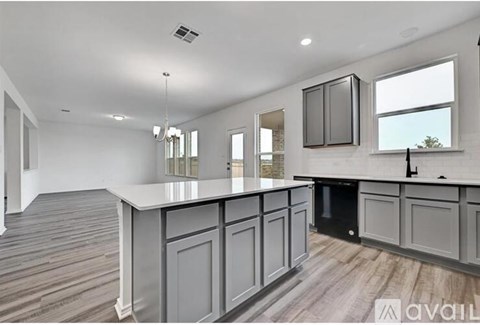 A modern kitchen with a large island and wooden flooring.