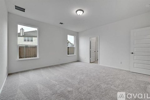 A spacious empty room with a carpeted floor and white walls.