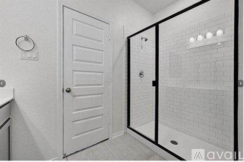 A white door is in a bathroom with a glass shower door.