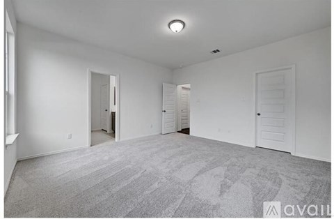 A room with a carpeted floor and two doors.