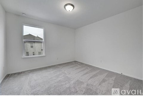 A room with a carpeted floor and a window showing a building outside.