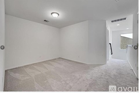 A spacious room with a carpeted floor and white walls.