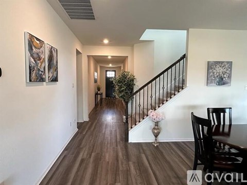A hallway with a staircase and a table with chairs.