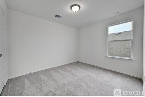A room with a carpeted floor and a window with blinds.