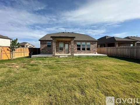 A house with a brown roof and a fence in front of it.