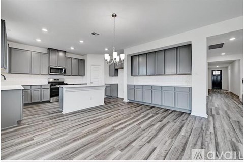 A spacious kitchen with wooden flooring and grey cabinets.