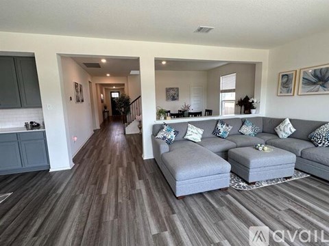 A living room with a grey couch and a wooden floor.