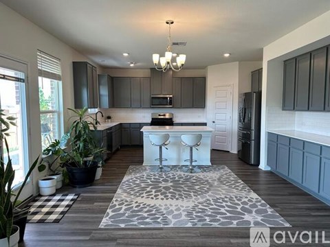 A modern kitchen with a white island and a checkered rug on the floor.