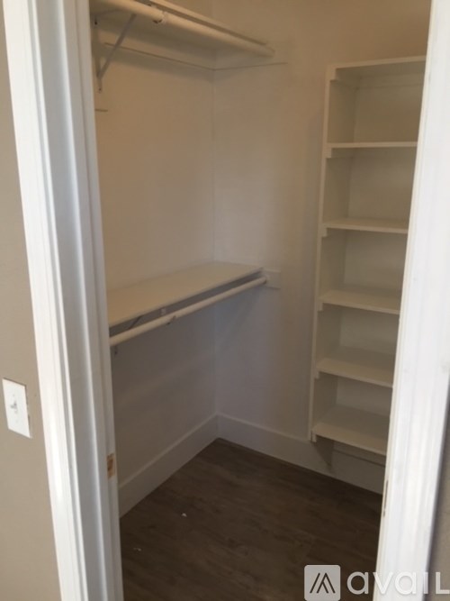 A white refrigerator with a white door is in a room with white walls and a white floor.