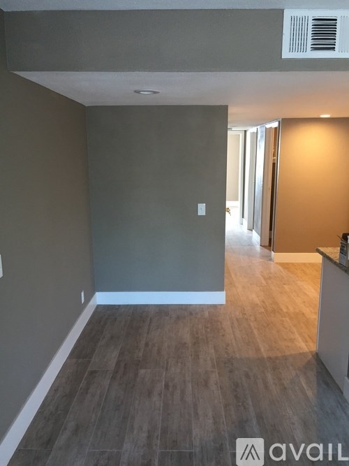 A room with a wooden floor and a wall with a light switch.
