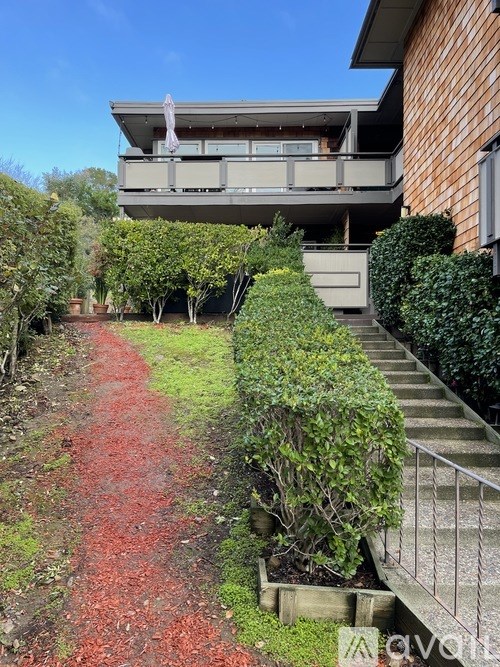 A red pathway leads up to a house with a balcony.
