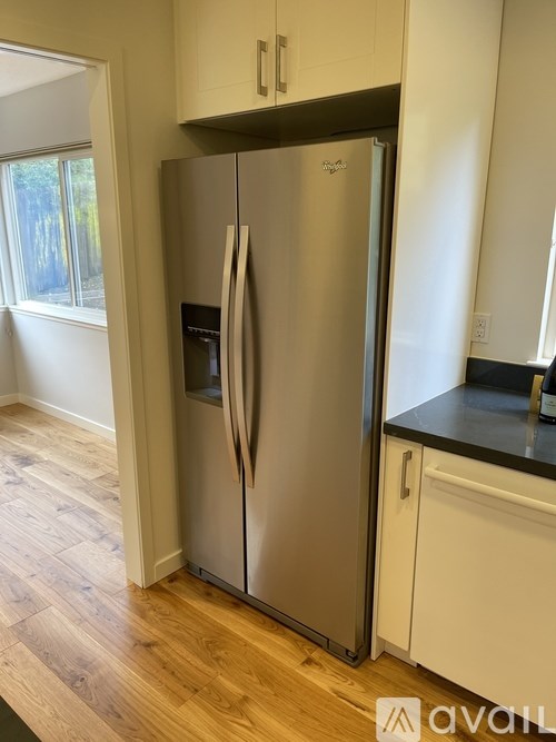 A stainless steel refrigerator with a black water dispenser is in a kitchen.