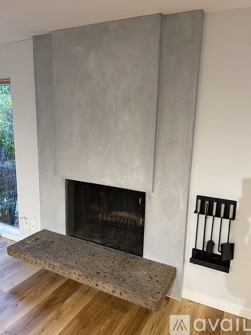 A modern fireplace with a grey stone surround and a concrete ledge in front of it.