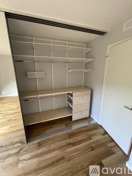 A large, empty pantry with a wooden floor and white walls.