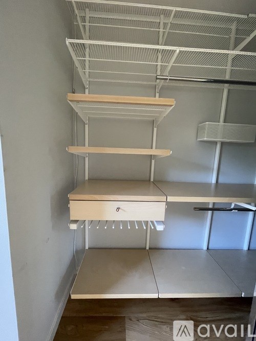 A white shelving unit with three shelves is mounted on a white wall.