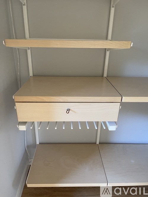 A white shelving unit with three shelves and a drawer.