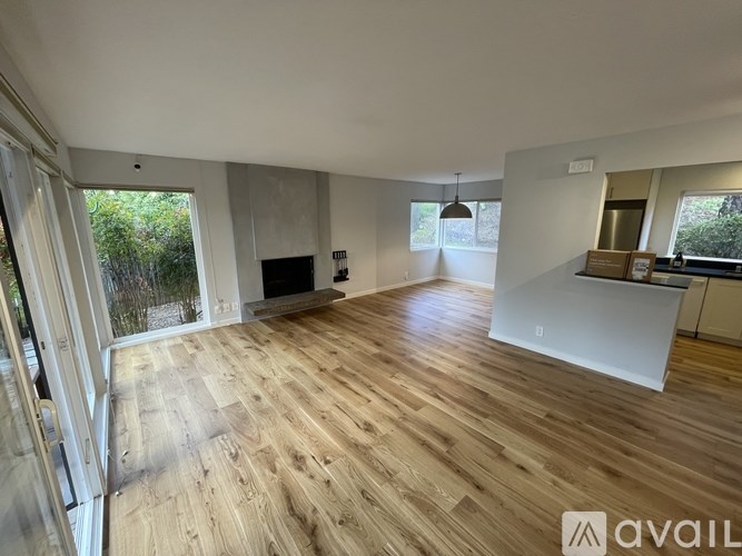 A spacious room with wooden flooring and a large window.