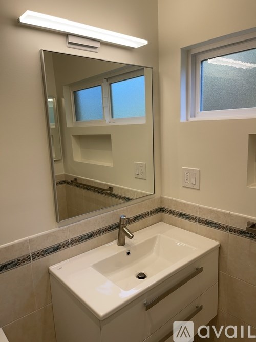 A bathroom with a sink, mirror, and window.