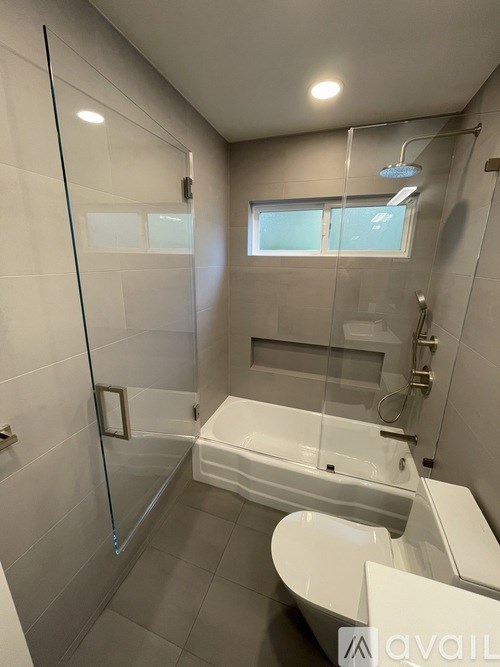 A modern bathroom with a glass shower enclosure and a white bathtub.