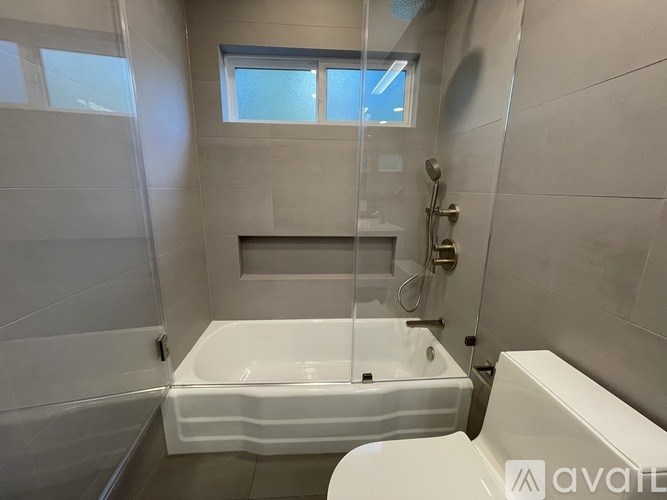 A white bathtub is in a bathroom with a window.