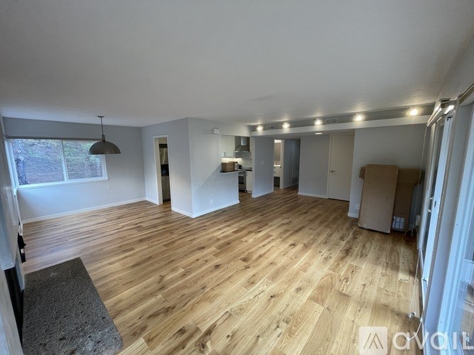 A spacious room with wooden flooring and white walls.